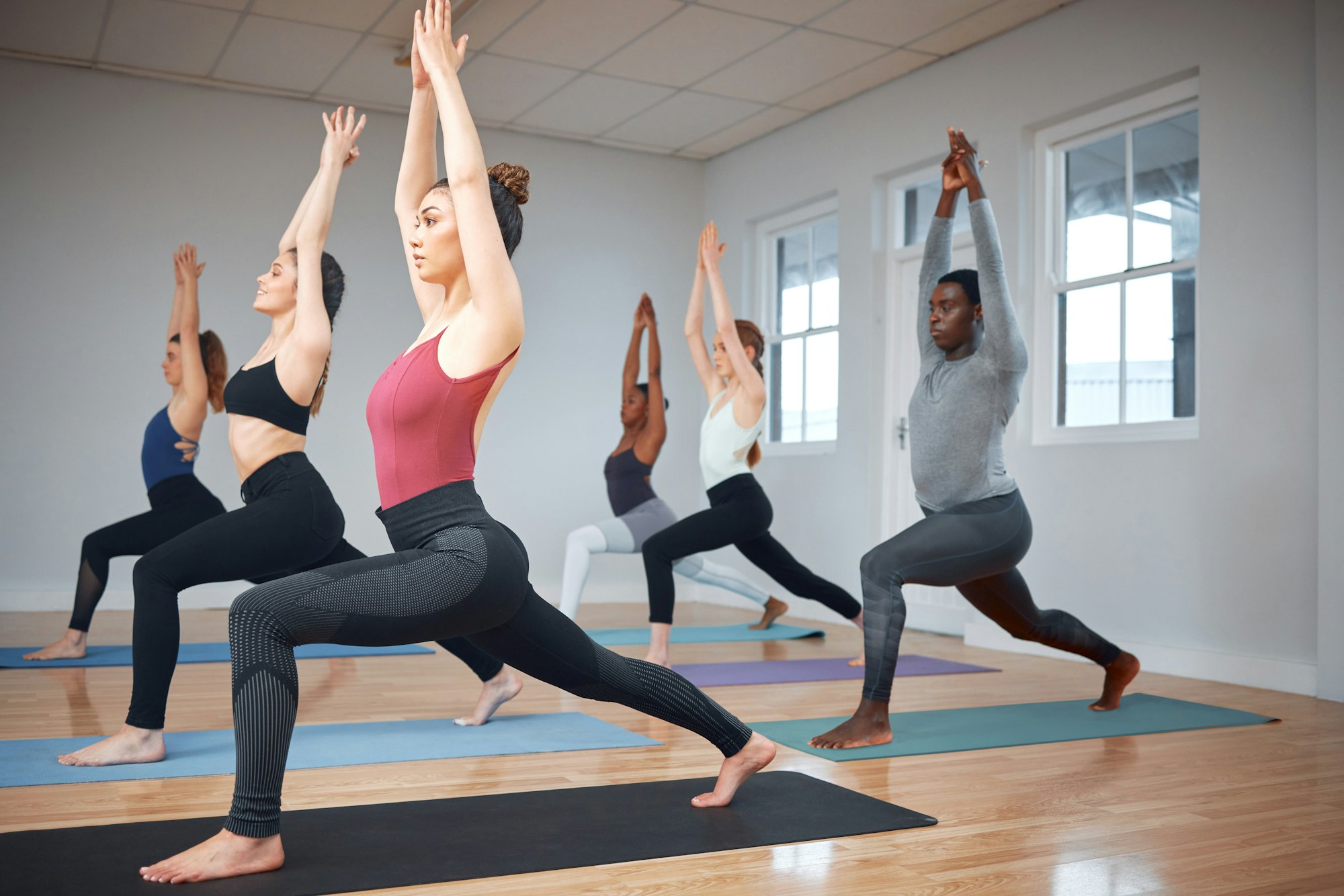 Shot of a group of yoga students completing lunges into the warrior pose during a class